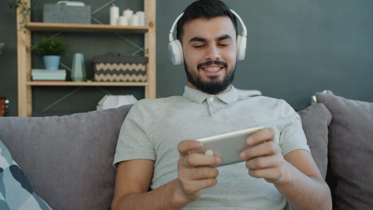 Man wearing headphones plays game on smartphone